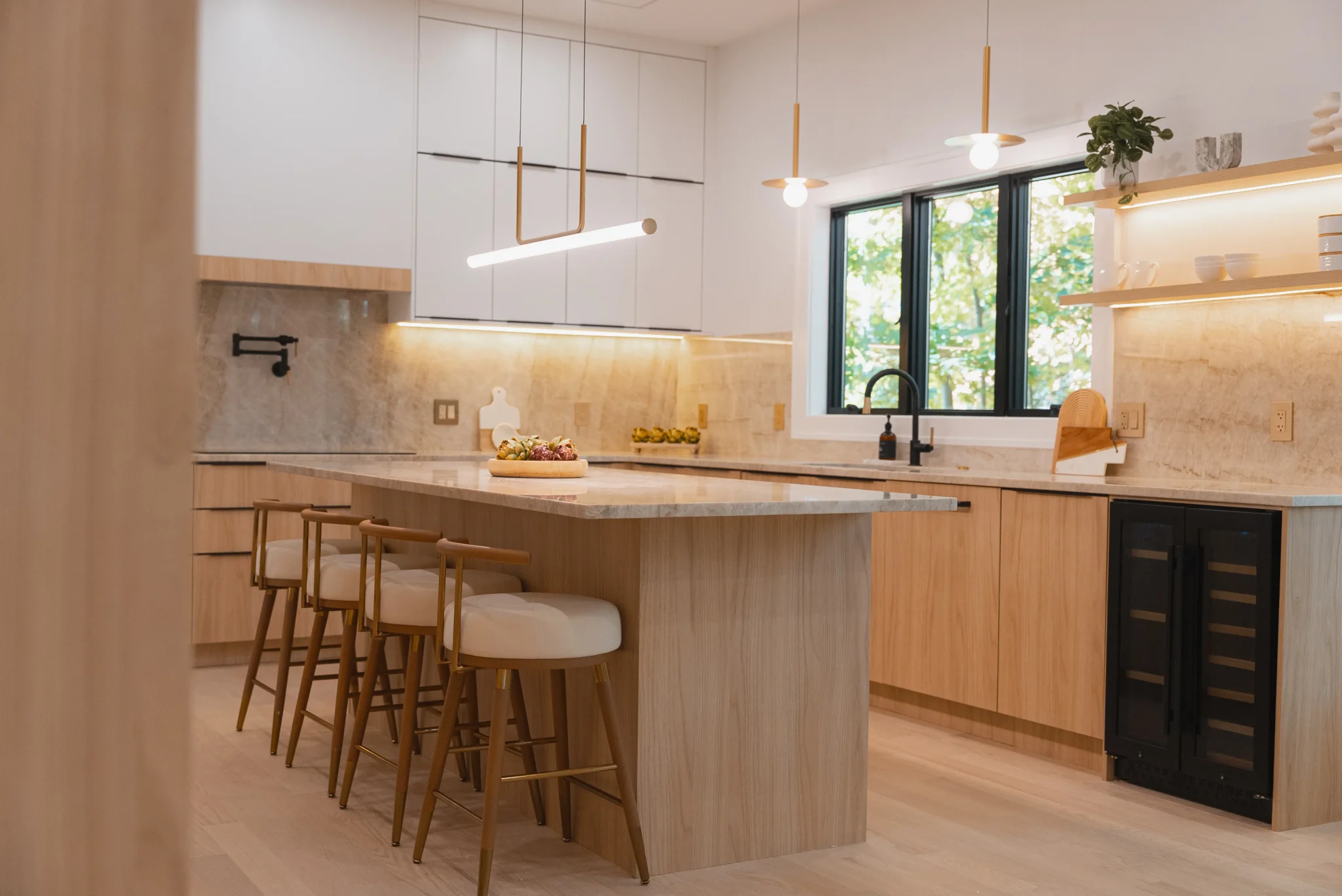 Modern kitchen with wood cabinetry, marble island, and warm ambient lighting