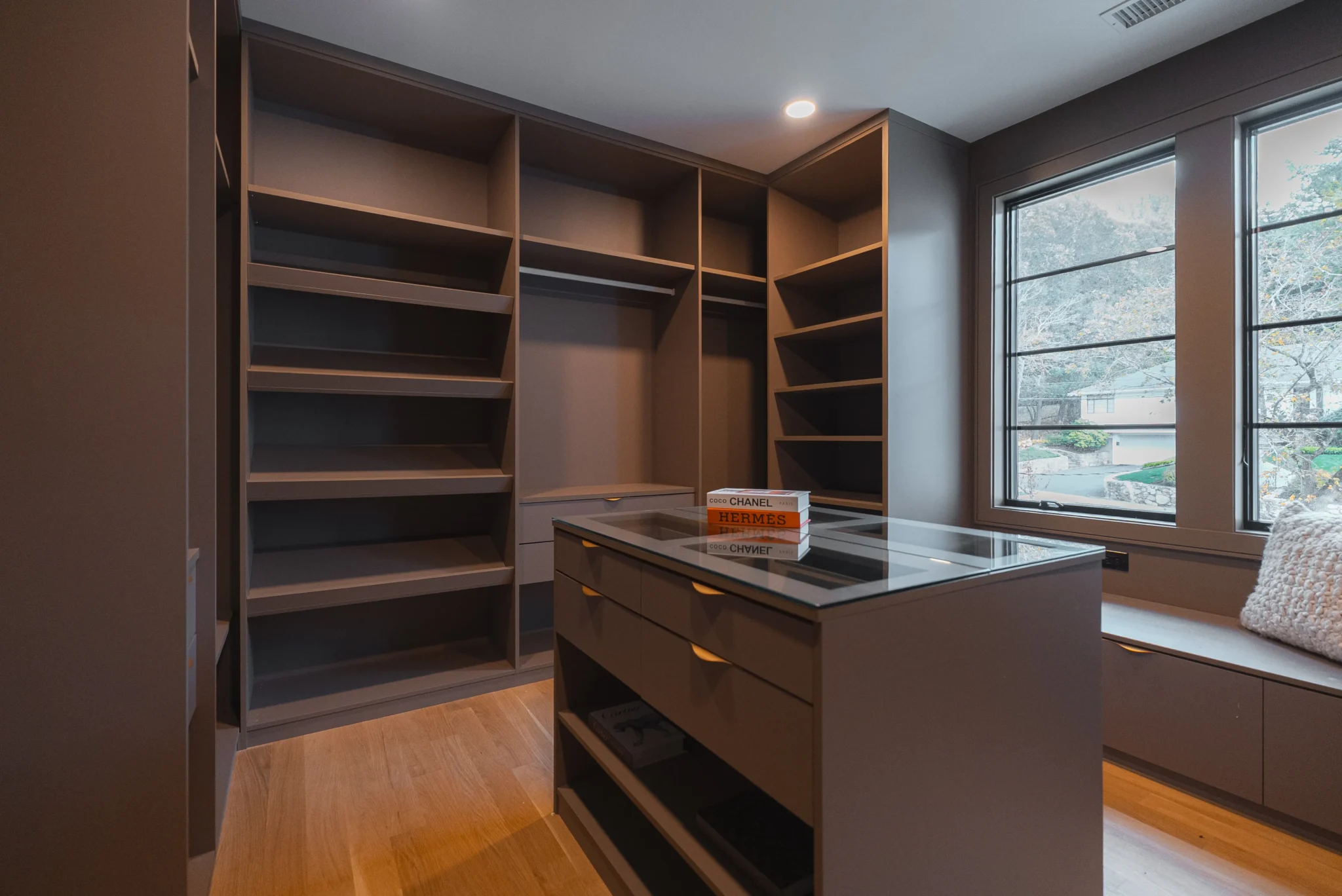 Custom walk-in closet with built-in shelving, central island, and natural light from large window