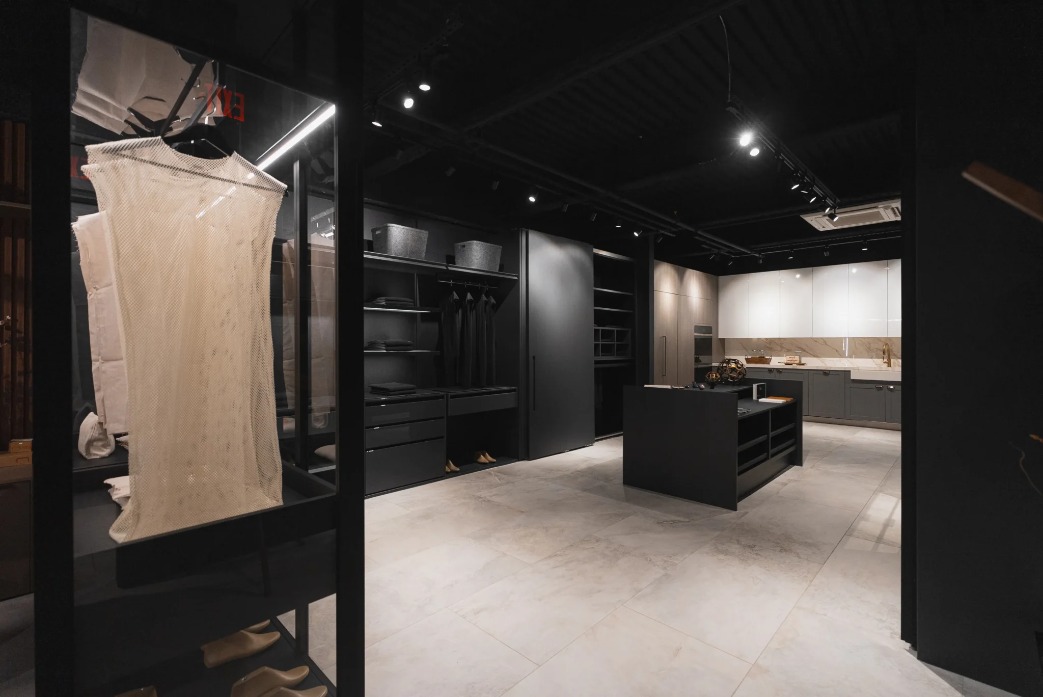 High-end showroom-style closet space with open layout, dark finishes, and central island storage