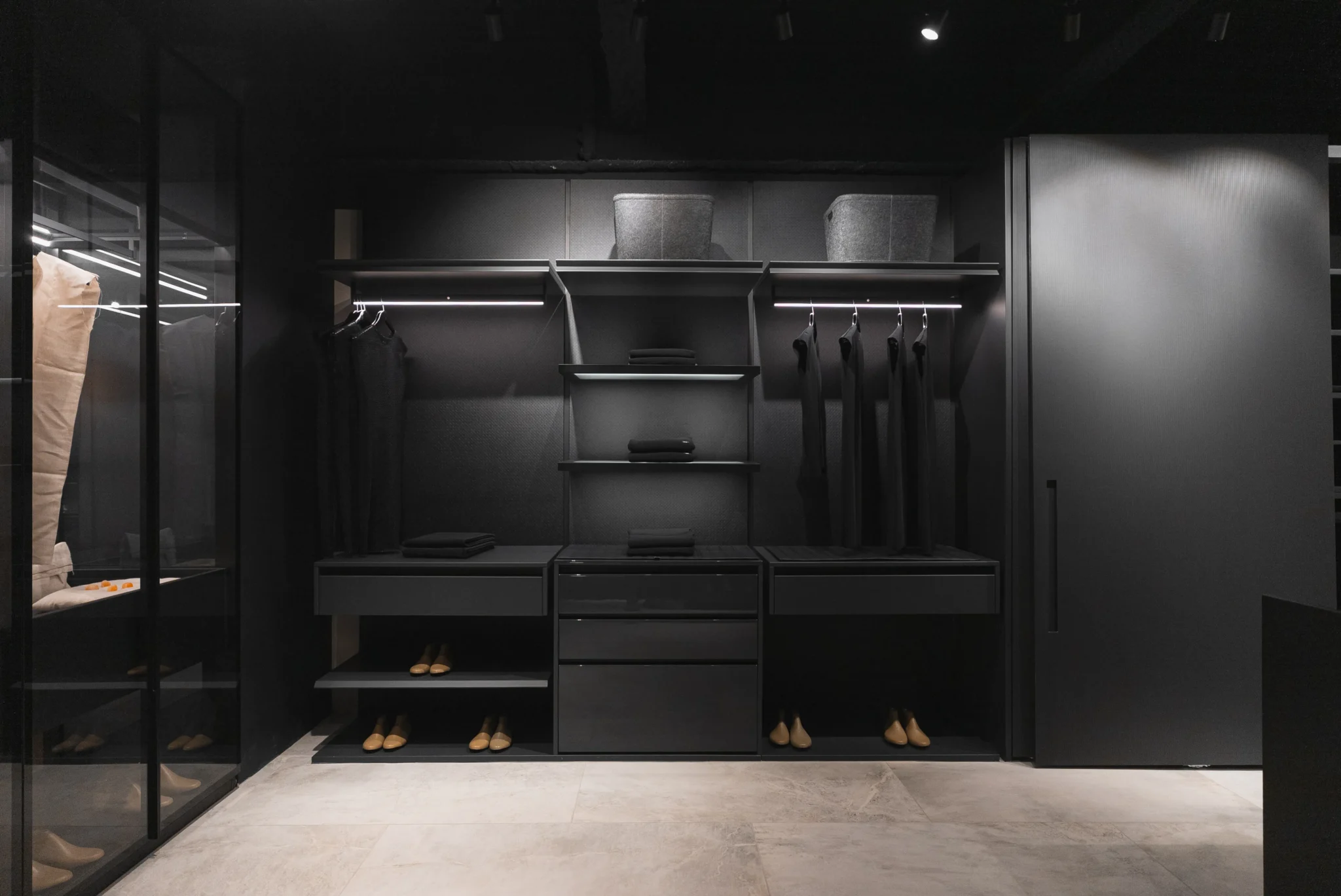 Luxury modern walk-in closet with matte black cabinetry, integrated lighting, and minimalist display layout