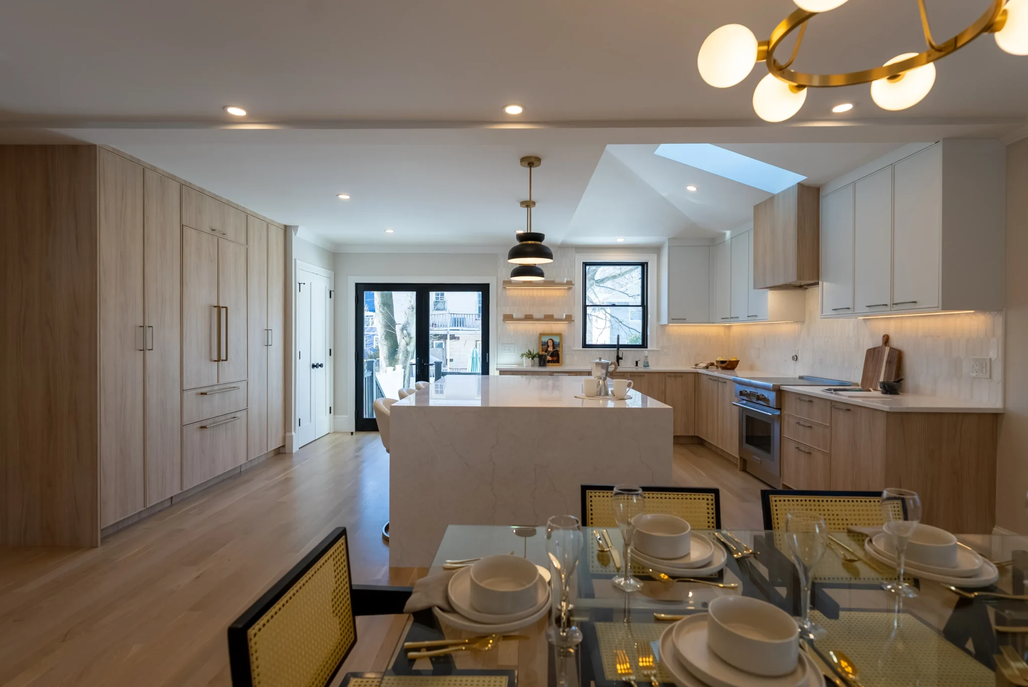 Open-concept kitchen and dining area with large island, warm wood cabinetry, and modern lighting