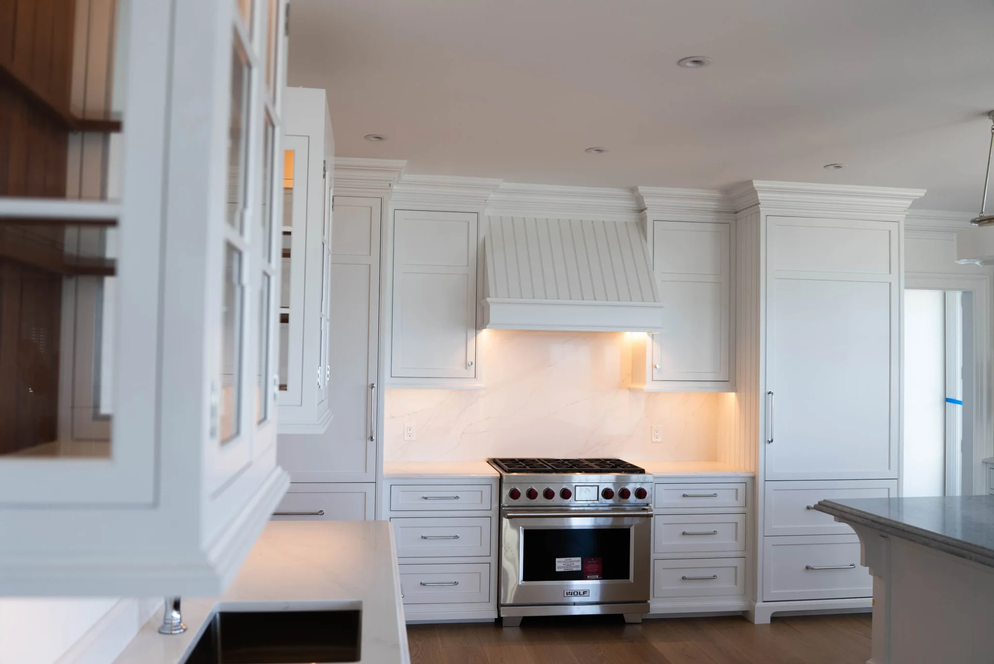 Classic white kitchen with custom cabinetry, professional range, and elegant crown molding